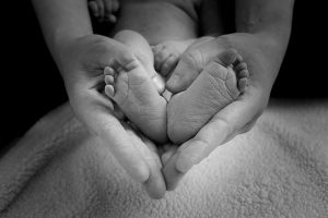 Hände umschließen Babyfüße als Herz